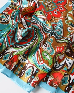 Detailed view of colorful paisley print satin scarf with smooth silk texture and blue hem