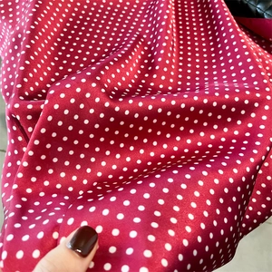 Detail of red silk-like fabric with white polka dots showing smooth soft texture