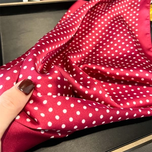 Detail of red satin scarf featuring white polka dot patterns and silky smooth texture