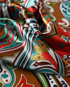 Macro detail of silky satin scarf showing intricate paisley patterns and glossy texture
