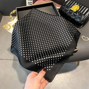 Macro view of silky black polka dot square scarf showing drape and smooth satin texture