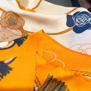 Close-up detail of luxury silk scarf with floral patterns and rolled edge stitching