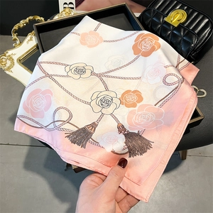 Detail of pink floral silk scarf with rose patterns and fringe print on a black tray