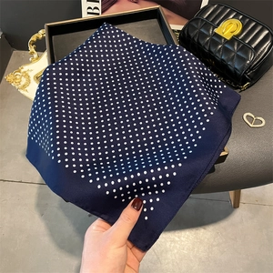 Detailed close-up of dark blue silk scarf with white polka dots and elegant glossy texture