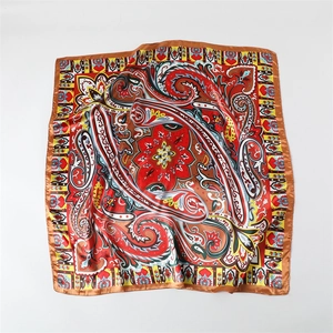 Detailed view of colorful paisley pattern on satin silk scarf with brown hem border