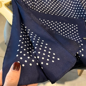 Close-up of navy blue polka dot silk scarf texture and fine stitched edges