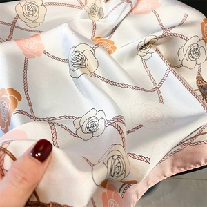 Close-up of silk scarf showing elegant rose prints and fine texture details