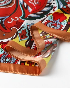 Close-up of vibrant paisley print satin silk scarf showing fine edge stitching detail