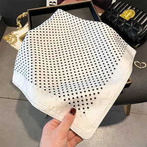 Detailed close-up of white silk-feel square scarf with classic black polka dots