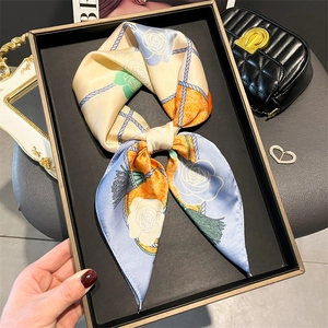 Elegant floral silk scarf with rose print and rope details tied in a bow on a display tray