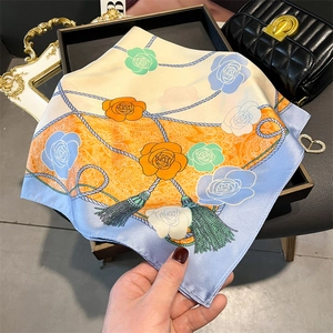 Detail shot of a floral silk scarf styled with a luxury handbag and pearl jewelry