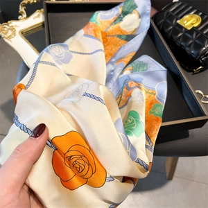 Detail of elegant silk-like square scarf showing floral prints and smooth satin texture