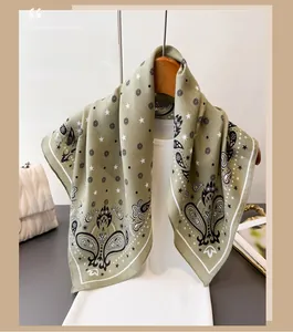 Close-up of sage green paisley silk scarf draped over a wooden hanger for styling