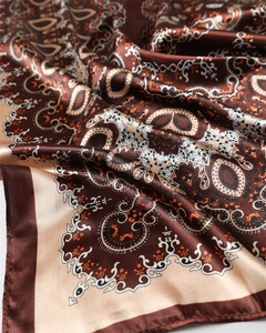 Détail d'un foulard en satin de soie avec motif paisley marron et texture brillante