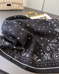 Detail of black paisley silk scarf featuring star patterns and fine white hemmed edges