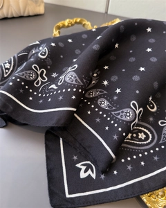 Detailed view of black paisley scarf with star prints and fine twill weaving texture