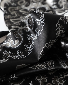 Vue détaillée de l'imprimé cachemire sur satin noir montrant sa texture soyeuse et brillante