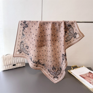 Close-up of paisley pattern silk scarf draped over a metal rod with a soft satin finish