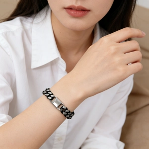 Detail of two-tone Cuban link bracelet featuring matte black and silver polished metal plate
