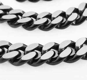 Macro close-up of a chunky black and silver two-tone stainless steel Cuban chain link