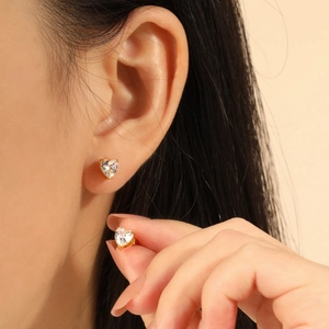 Minimalistisches Herz-Zirkon-Ohrring-Set mit goldener Basis am Ohr und in den Fingern