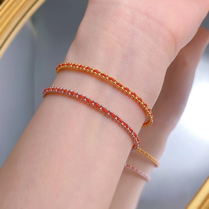 Nahaufnahme minimalistischer geflochtener roter Armbänder mit Gold- und Silberperlen