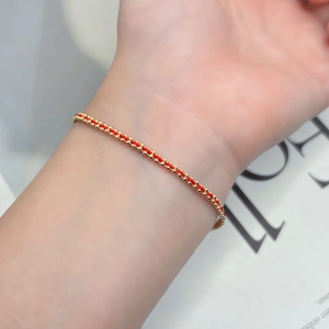 Detailansicht des handgefertigten roten Armbands mit 18K Goldperlen am Handgelenk