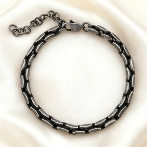 Macro detail of retro stainless steel chain links with lobster clasp on silk fabric