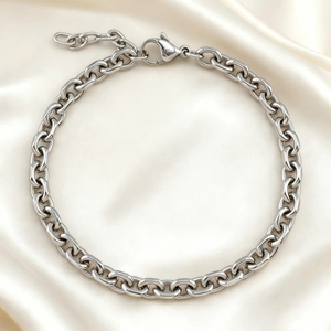 Close-up of polished stainless steel cable chain bracelet with lobster clasp on silk fabric