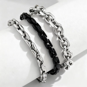 Detailed view of three stainless steel bracelets in silver and black on white pedestals