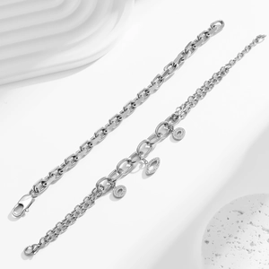 Detail of silver stainless steel chain bracelets with charms on white stone base