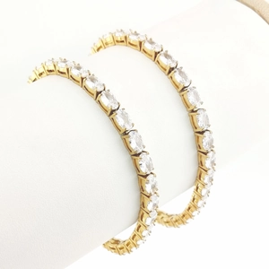 Détail d'un bracelet de tennis plaqué or avec zircons ovales sur un présentoir blanc