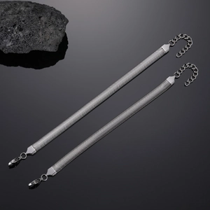Macro detail of silver flat snake chain bracelets with lobster clasp on volcanic rock