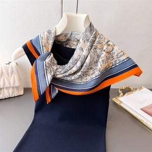 Détail d'un foulard en soie avec imprimé forêt à l'encre et bordure orange sur tricot