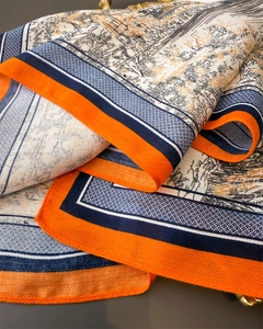 Détail de la texture sergé et de l'imprimé paysage sur un foulard orange et bleu