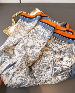 Détail d'un foulard en soie avec imprimé paysage classique et bordure orange