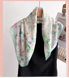 Détail d'un foulard en soie aux motifs floraux élégants rose et vert sur tissu léger