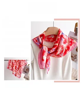 Détail d'un foulard élégant en soie à fleurs roses avec des bords roulés raffinés
