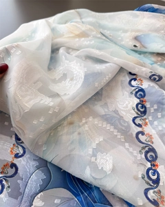 Close-up of lightweight blue silk scarf showing detailed embroidery and soft texture