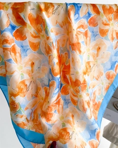 Détail d'un foulard en soie montrant des motifs floraux et une texture satinée