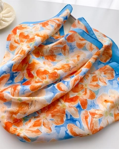 Détail d'un foulard en soie avec imprimé floral orange et bordure bleu ciel élégante