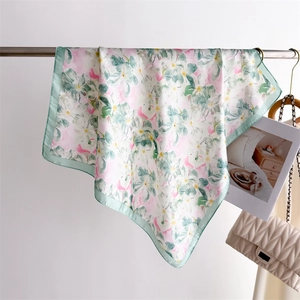 Gros plan détaillé d'un foulard en soie à fleurs rose et vert sur un support métal