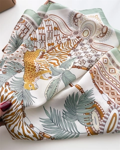 Detailed view of silk square scarf featuring leopard and tropical leaf prints with soft drapes