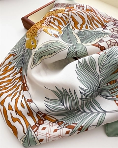 Detail of silk scarf with leopard print, tiger stripes and palm leaves on a wooden tray