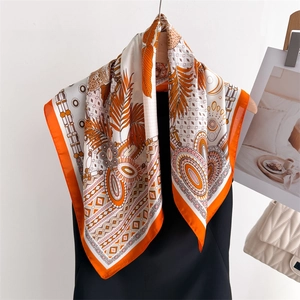 Orange wild print silk scarf with leopard and tropical leaf patterns on a wooden hanger
