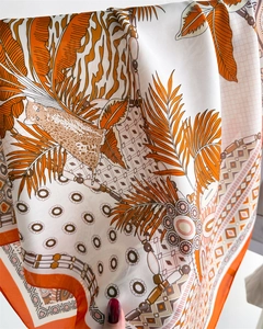 Detailed view of satin scarf with orange tropical palm leaves and leopard print patterns