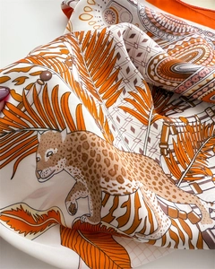 Detail of silk scarf showing vibrant leopard and palm leaf print with smooth texture
