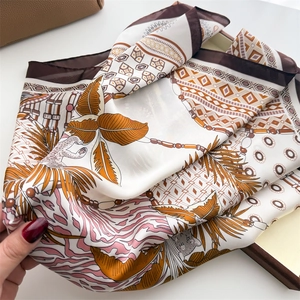 Close-up of elegant silk scarf with leopard and palm leaf print showing smooth texture
