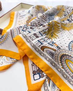 Close-up of yellow silk scarf with leopard print and geometric patterns on a tray