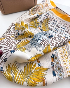 Detailed view of silk scarf with leopard and tropical palm patterns on a leather bag